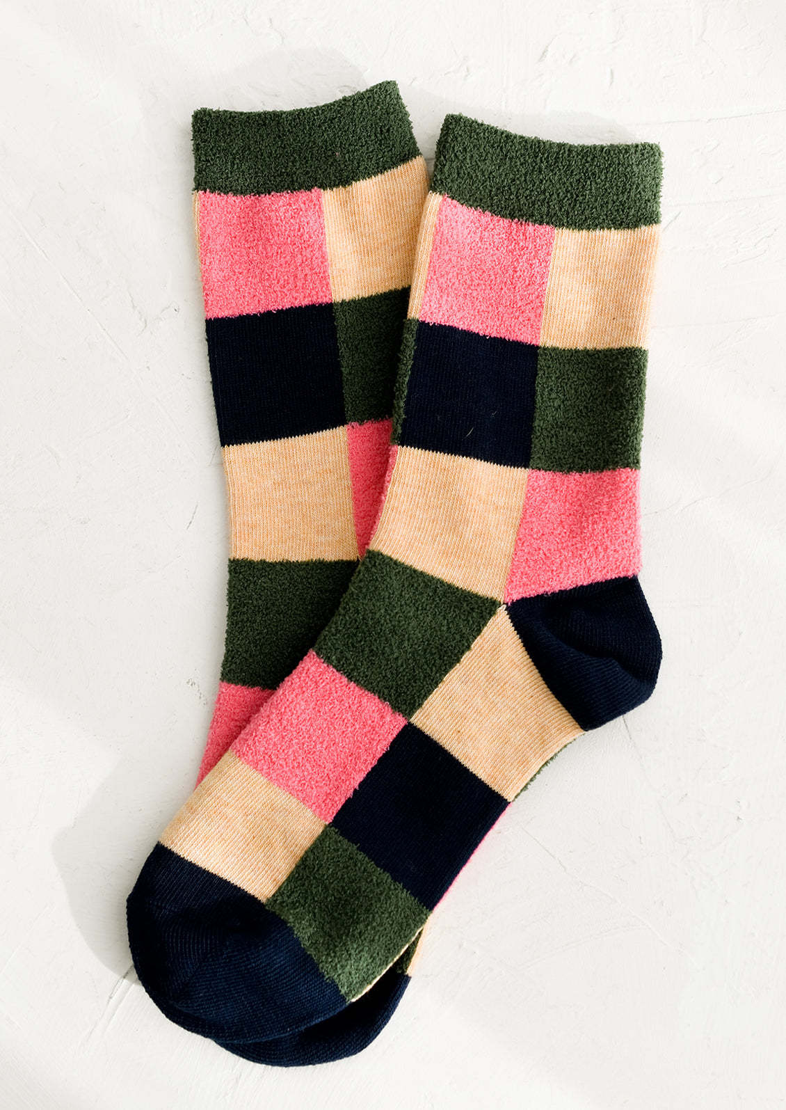 A pair of checkered socks in peach, navy and pink with fuzzy olive accents.