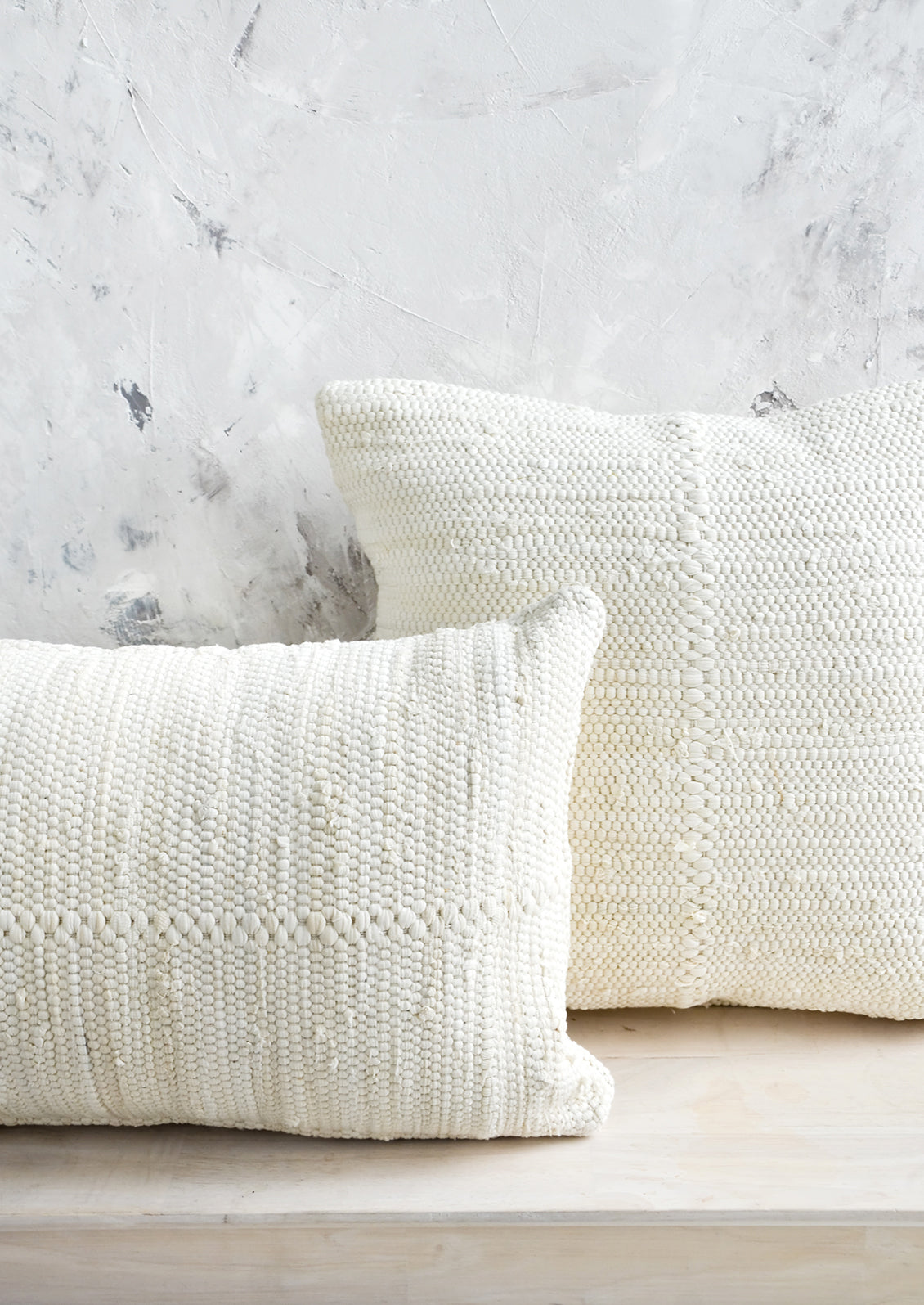 Two throw pillows in square and lumbar sizes, made from cream colored cotton chindi fabric.