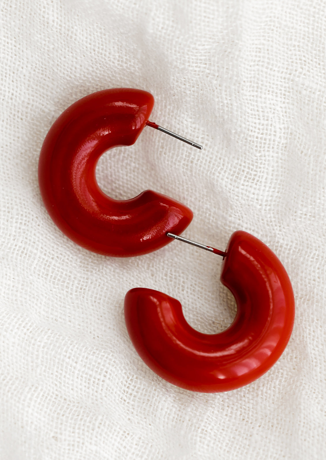 A pair of chunky gloss finish hoop earrings in crimson red.