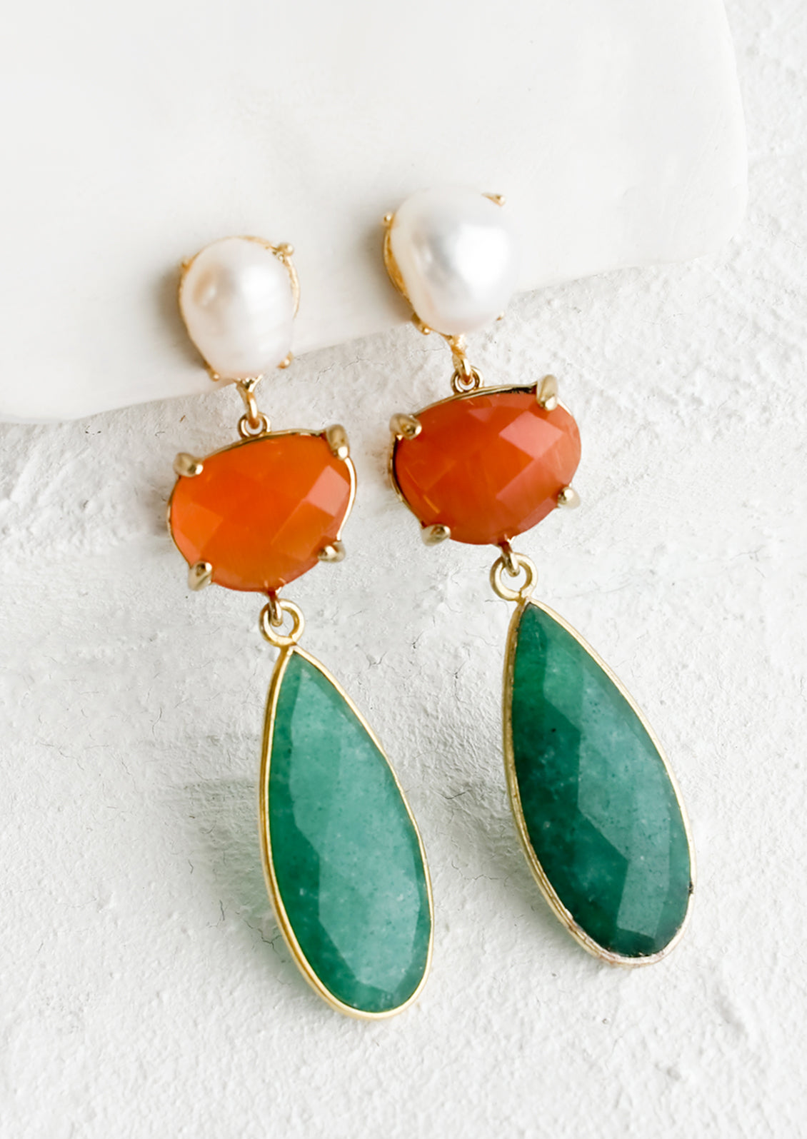 A pair of earrings with pearl post and orange and green gems.
