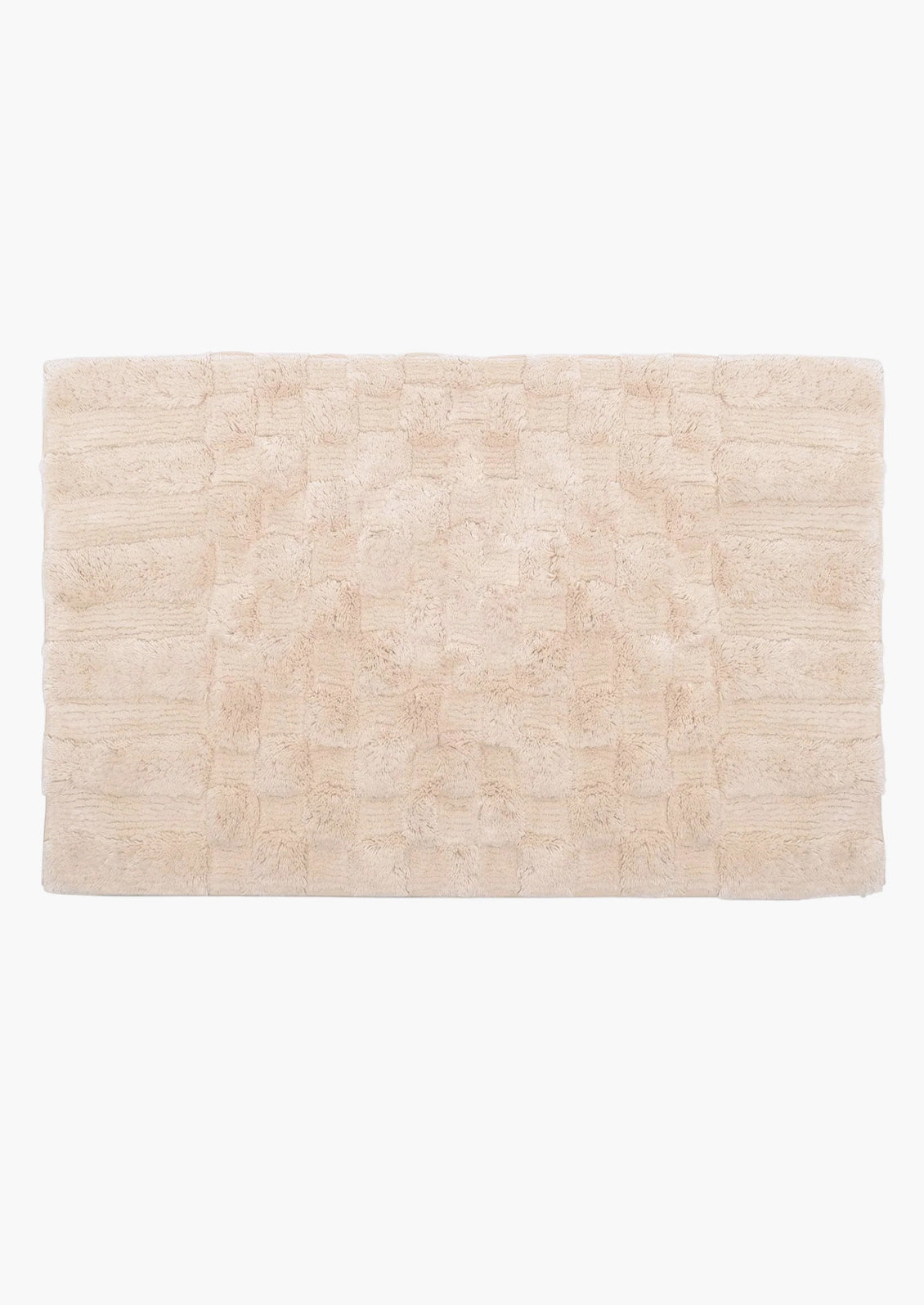 A light pinkish cream bath mat with textured checker pattern.