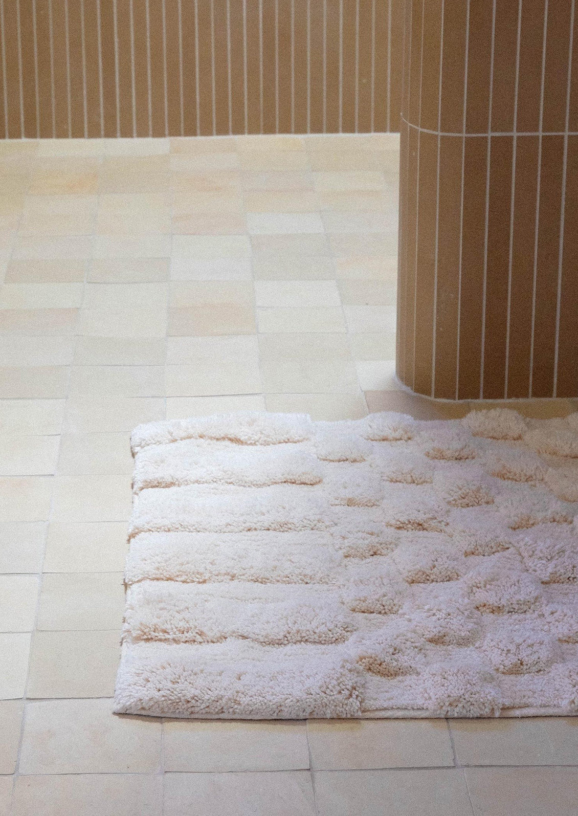 A light pinkish cream bath mat with textured checker pattern.