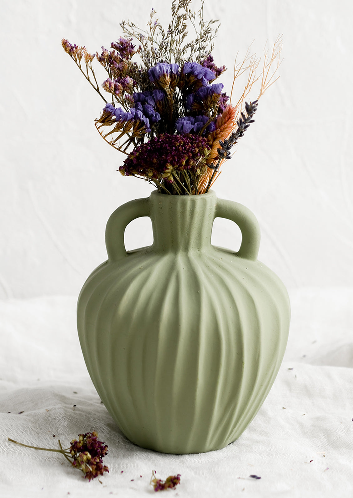 A mint green ceramic vase with handles at sides and carved line texture.