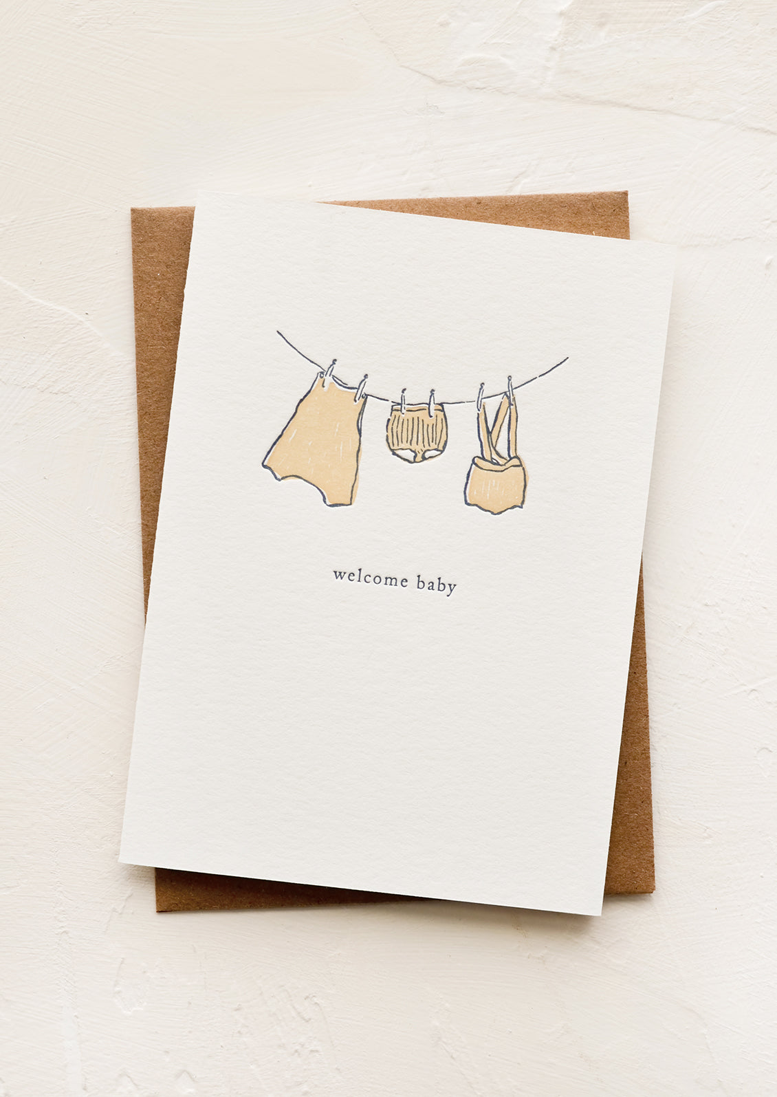 A greeting card with baby clothes hung on a clothesline.