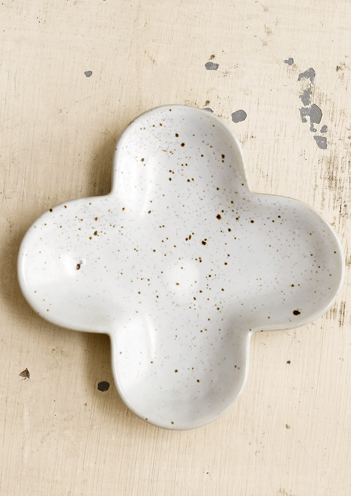 A clover shaped little dish in speckled white ceramic.