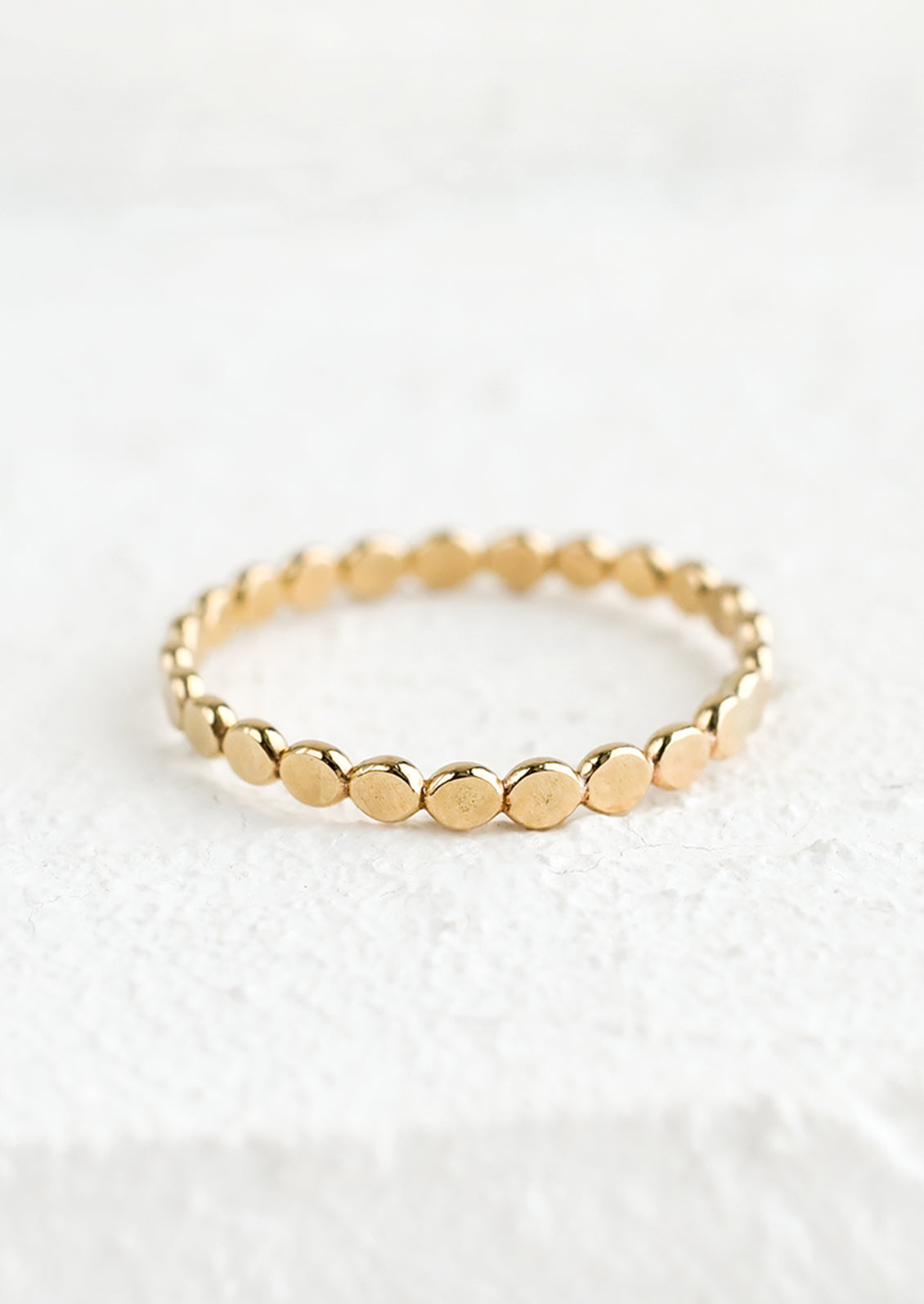 A gold stacking ring made from round discs.