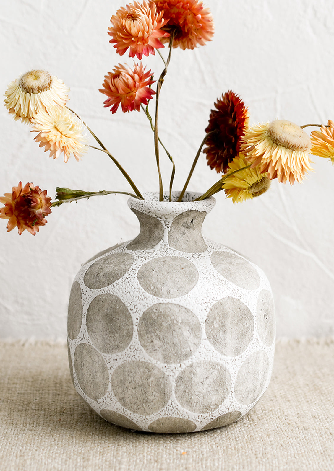 A round vase with narrow neck, in white with grey polka dot print.