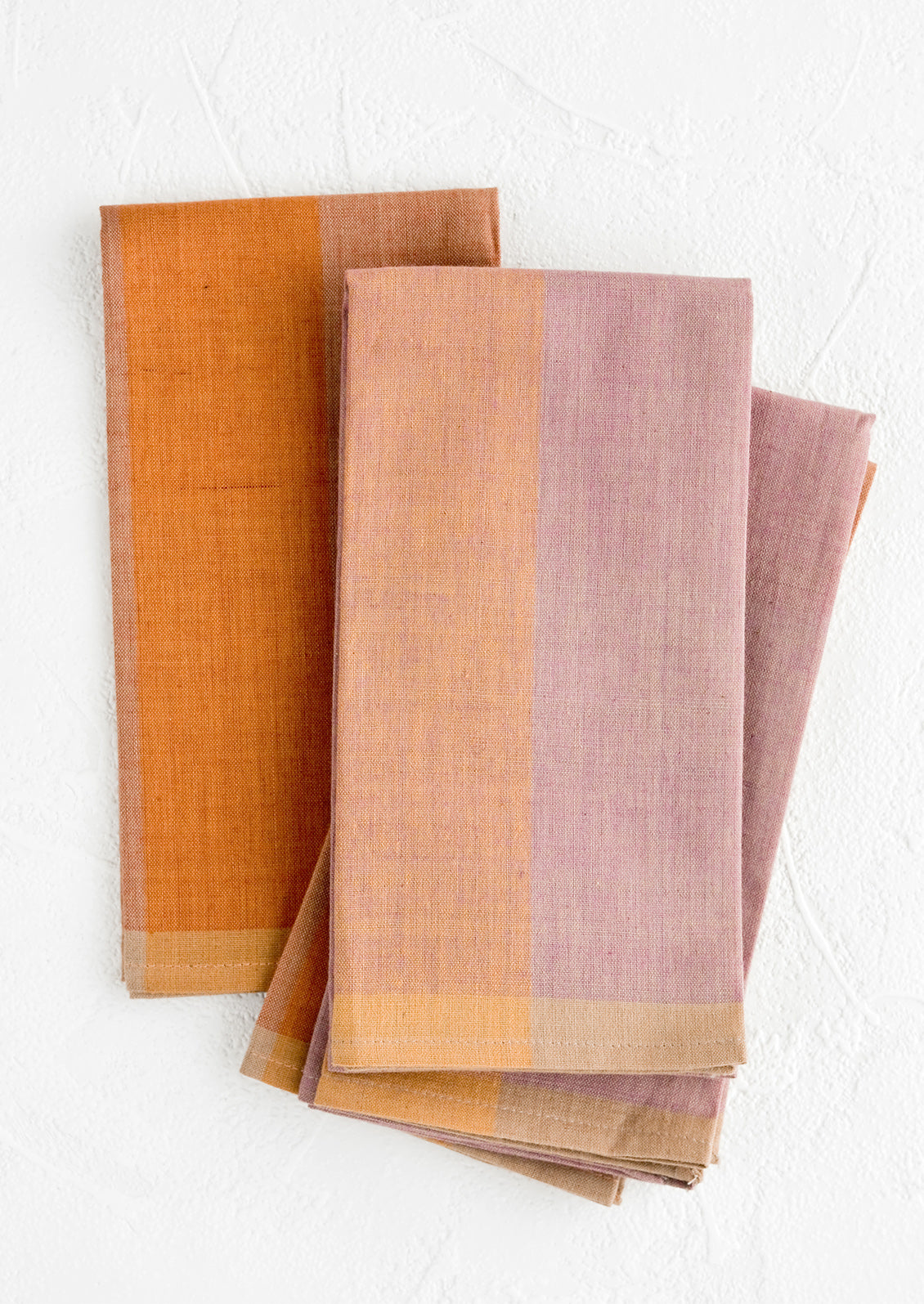 A stack of fabric napkins in purple and orange colorblock design.