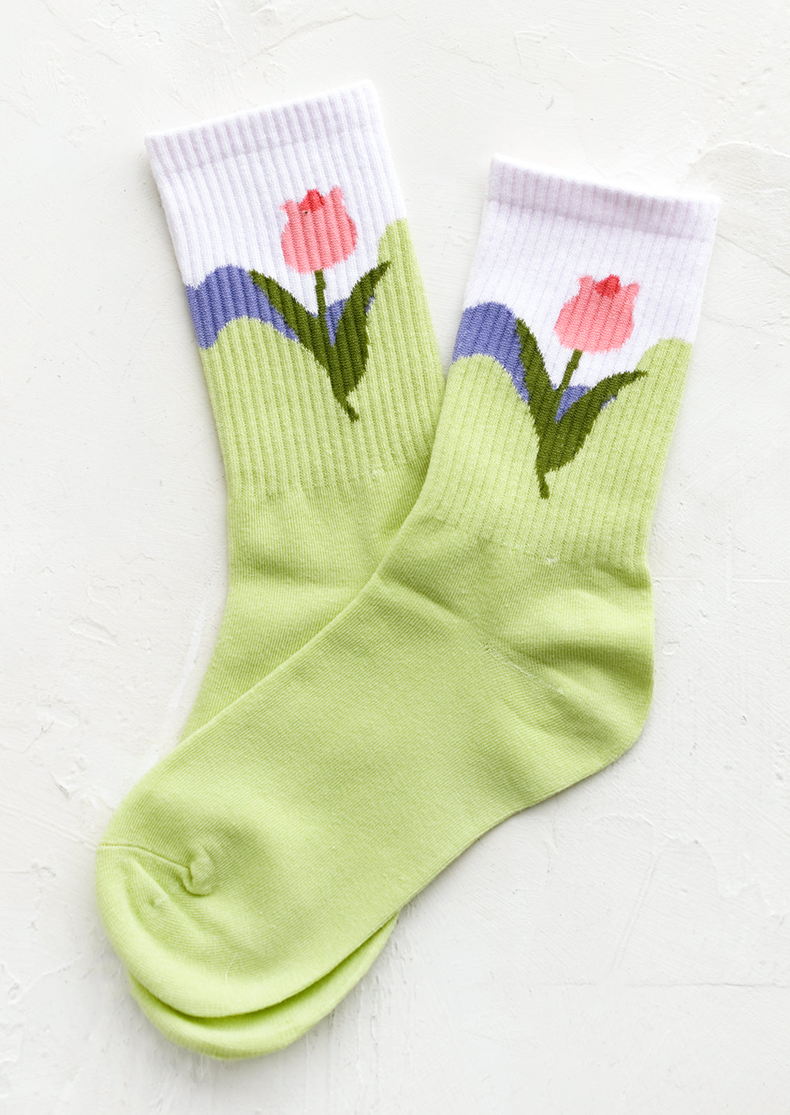 A pair of socks in lime green with pink tulip design at ankle.