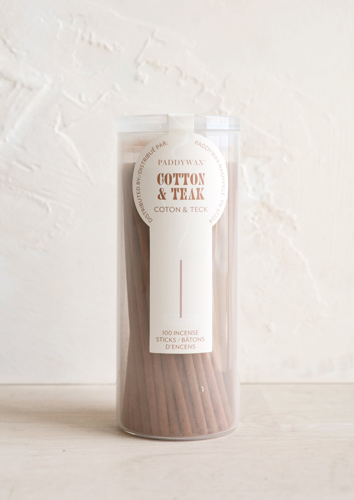 A white glass jar with incense sticks in cotton & teak scent.
