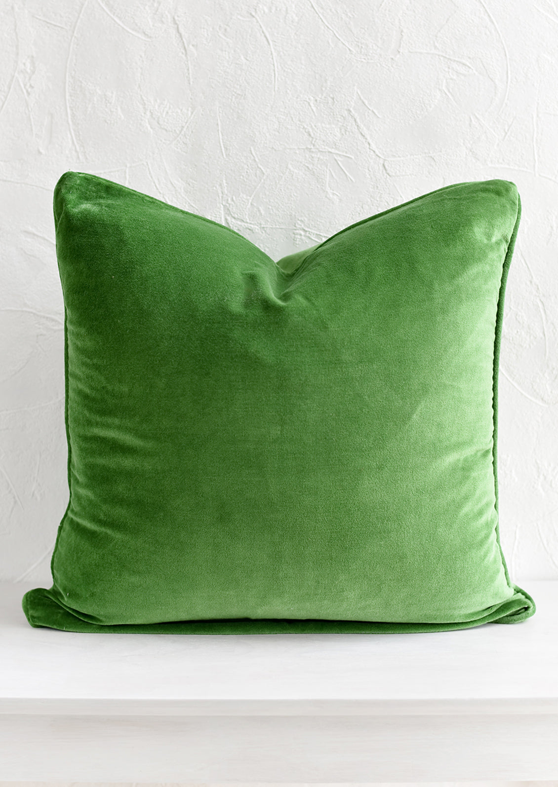 A square velvet throw pillow in fern green.