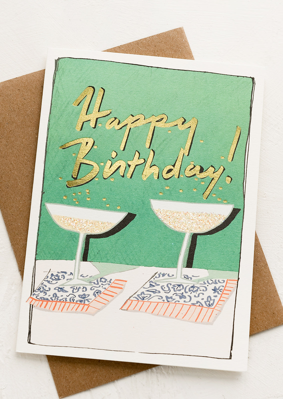 A birthday card with glittering coupe glasses reading "happy birthday!'.