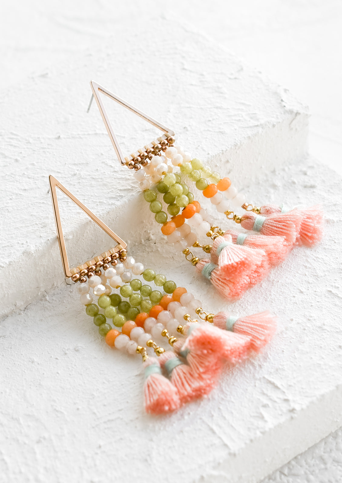 A pair of beaded earrings with tassel detail and triangle base.