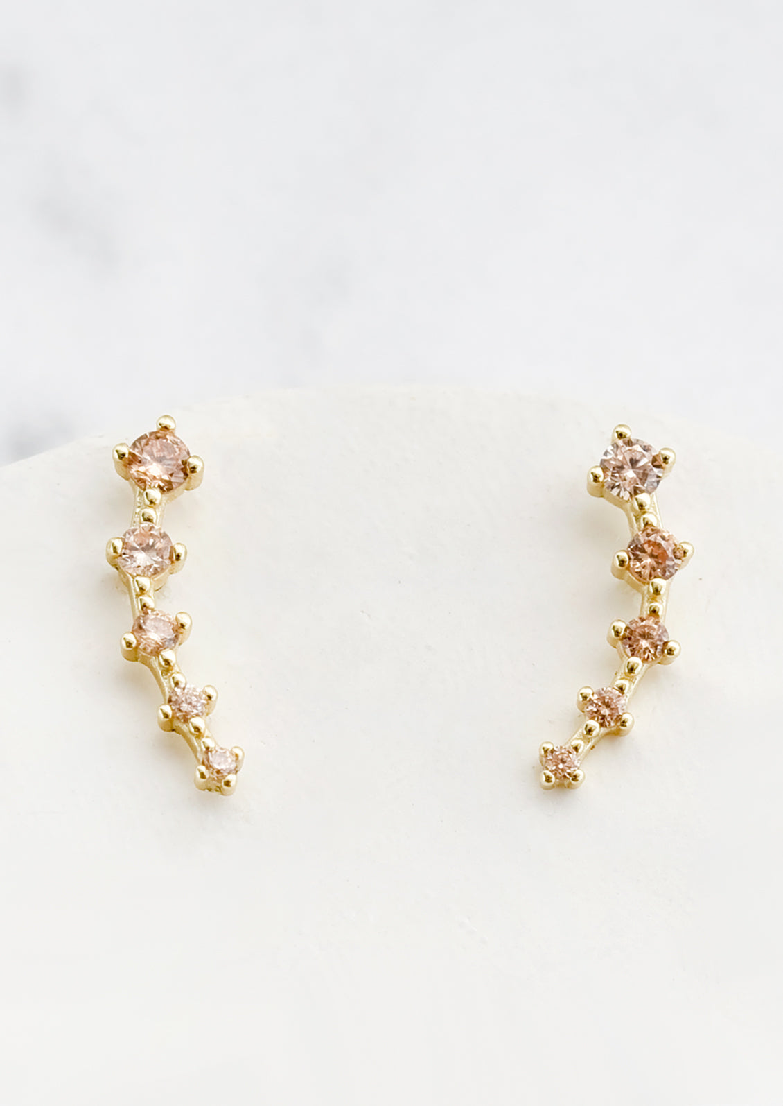 Stud earrings with champagne crystals in incremental sizes, designed to climb up the ear