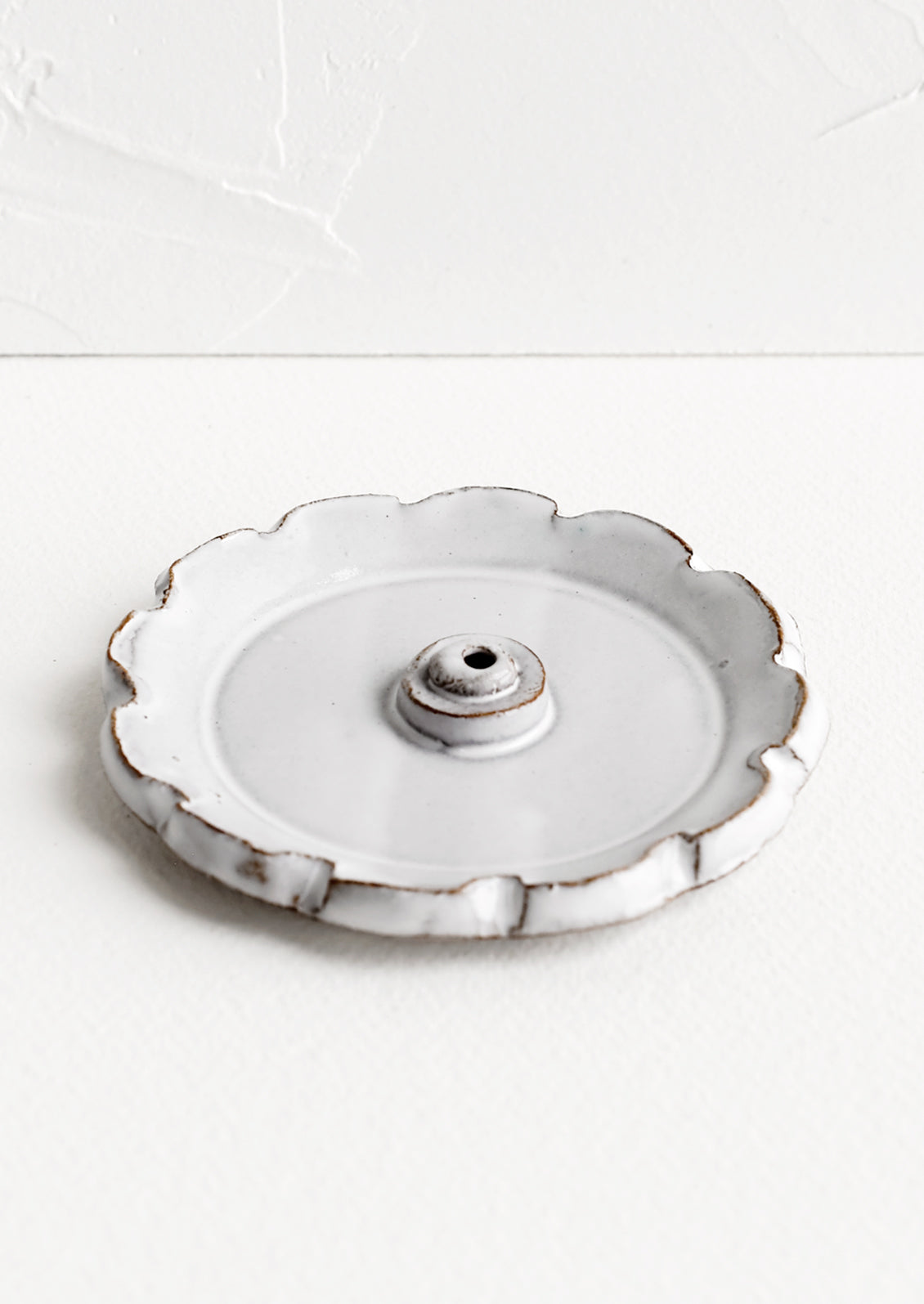 A flower shaped ceramic incense holder in white glaze.