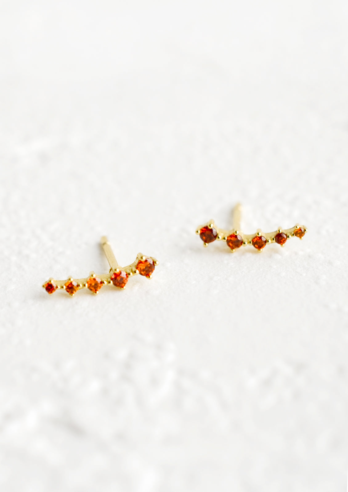 Stud earrings with amber crystals in incremental sizes, designed to climb up the ear