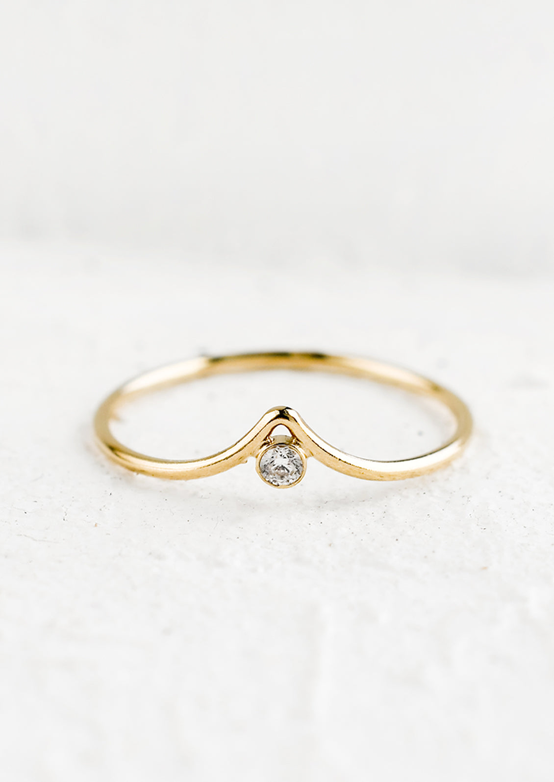 A gold ring with pointed center and single crystal bezel.