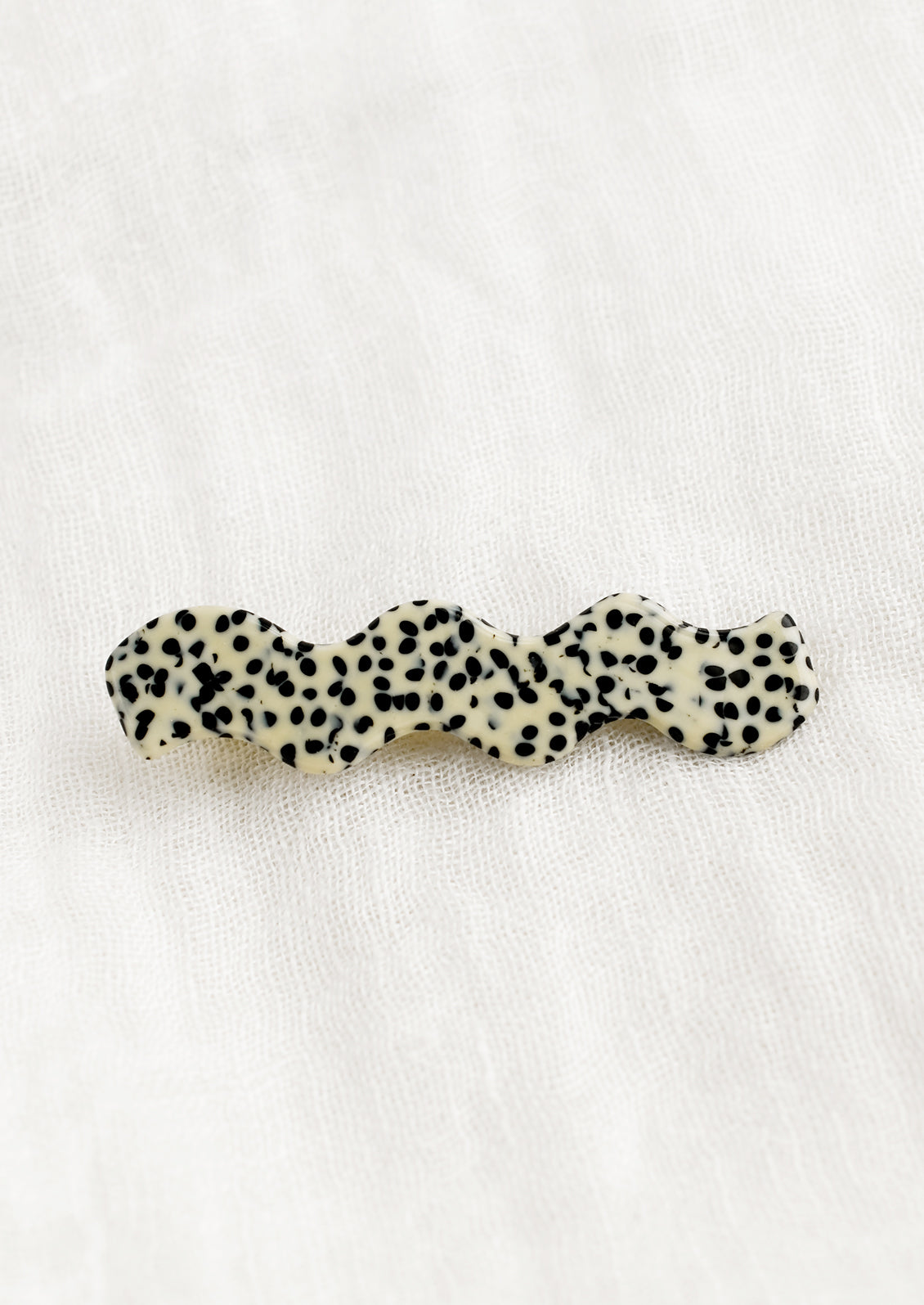 A wavy hair barrette in black and white spot print.