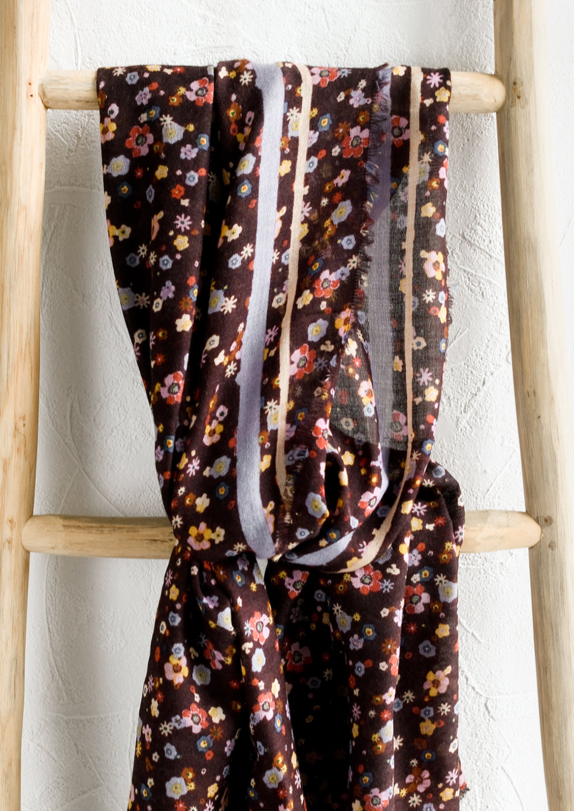 A floral print scarf with brown background and yellow and lilac border.