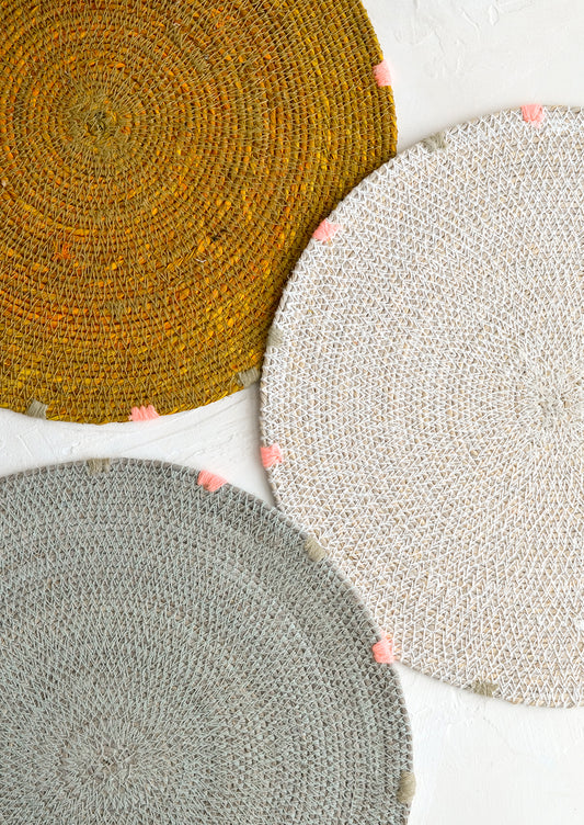 Three round seagrass placemats in assorted colors.