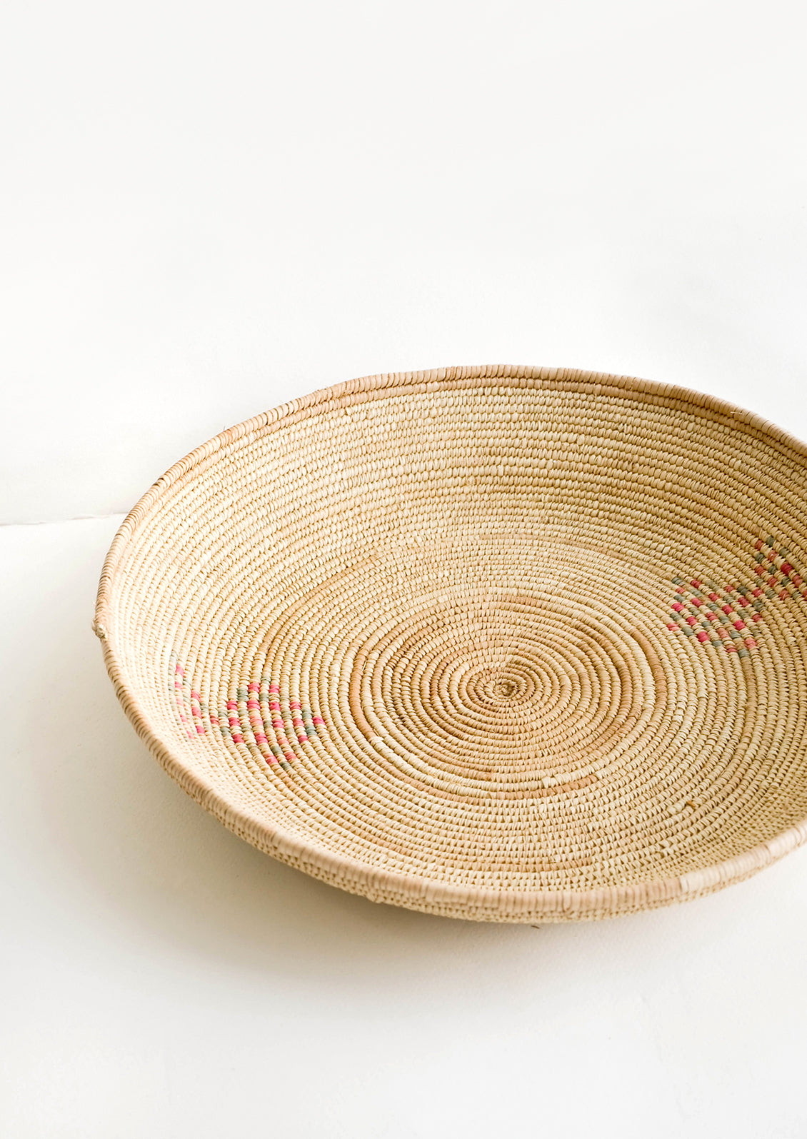 Woven platter made from date palm with pink and green design