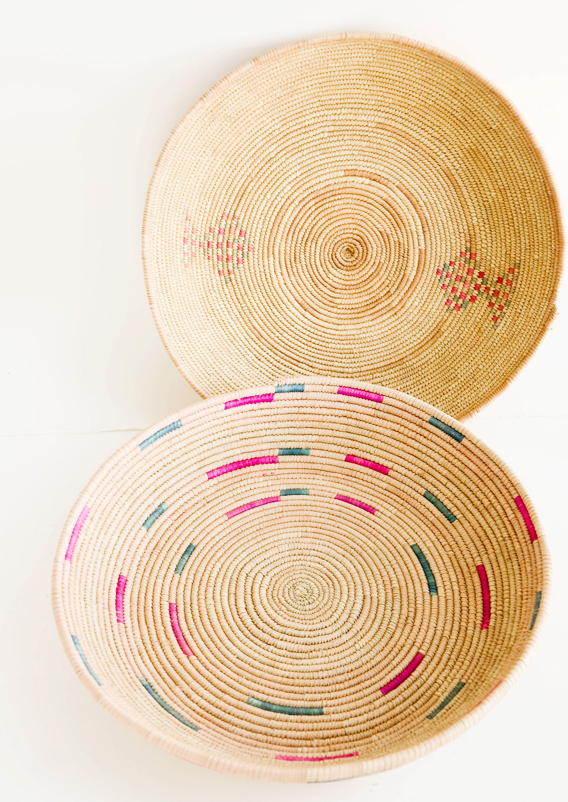 Round, woven platter made from date palm with pink and green design