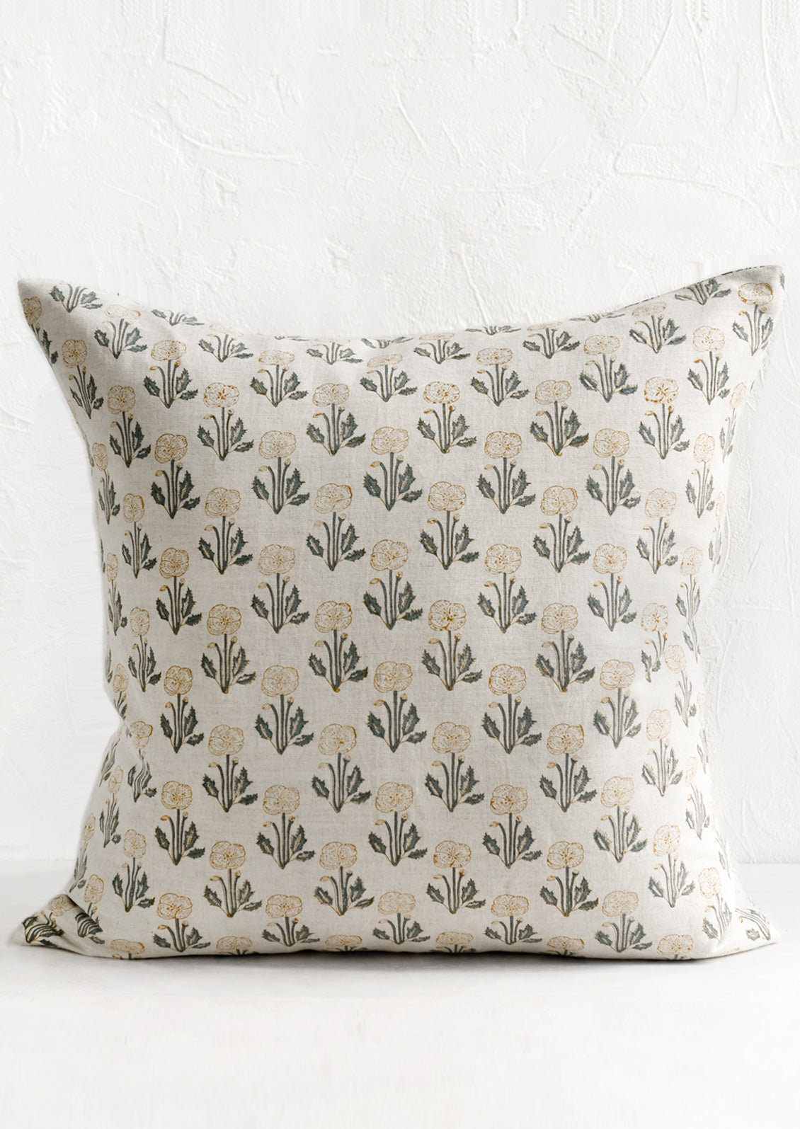 A natural linen throw pillow with floral block print pattern.