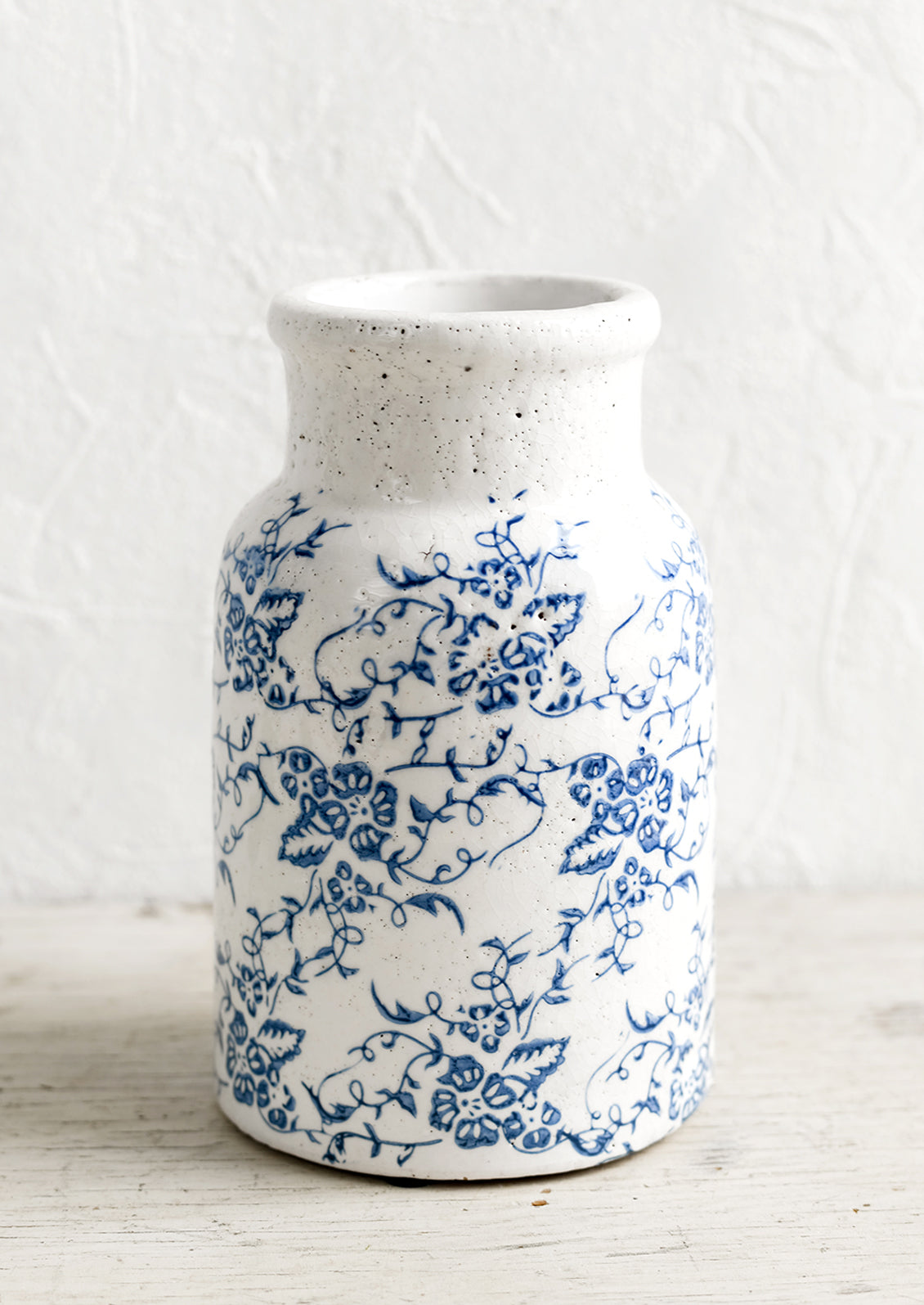A blue and white ceramic vase with antique floral print.