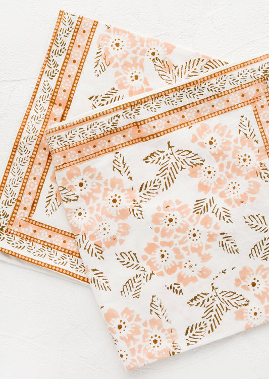 A pair of cotton napkins with peach and brown floral print.