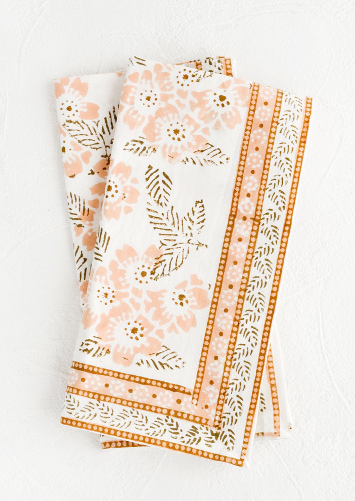 A pair of cotton napkins with peach and brown floral print.