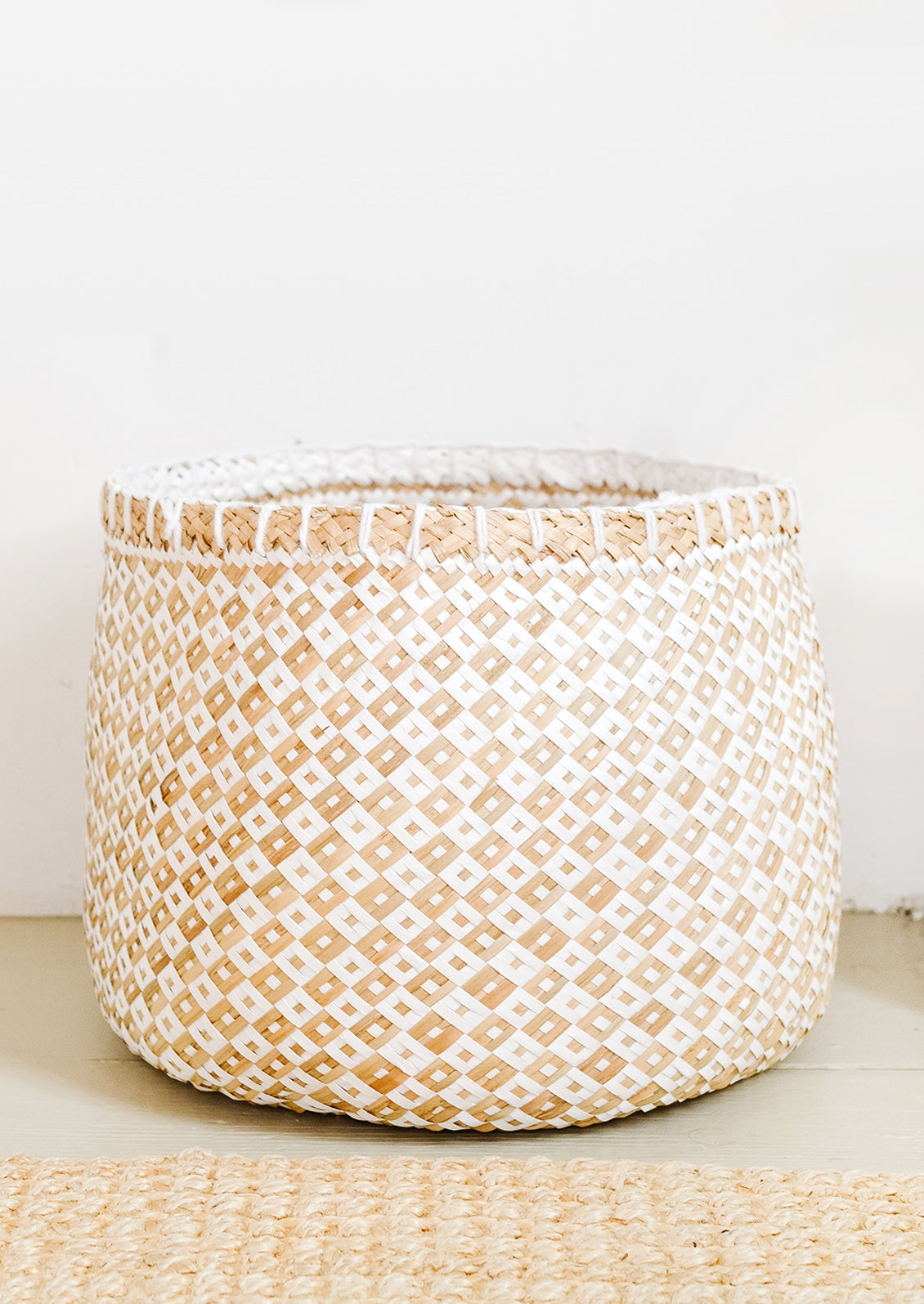 A round storage basket in natural straw and white paper.