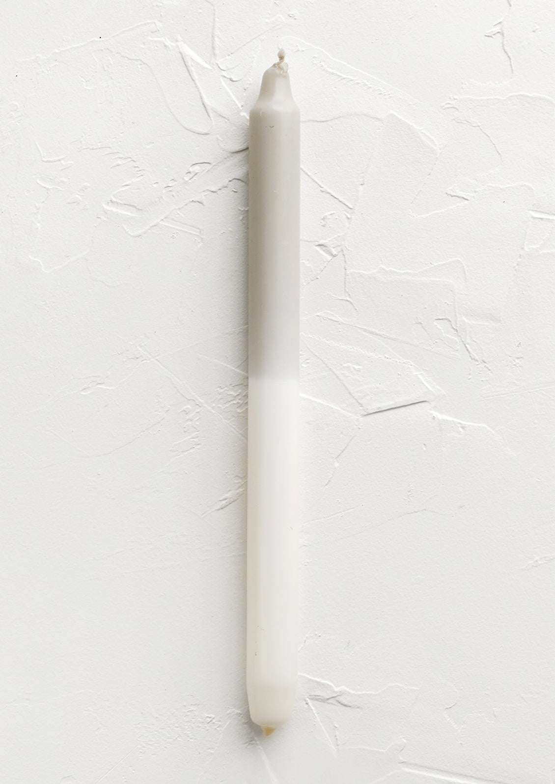 A straight taper candle in taupe and white.