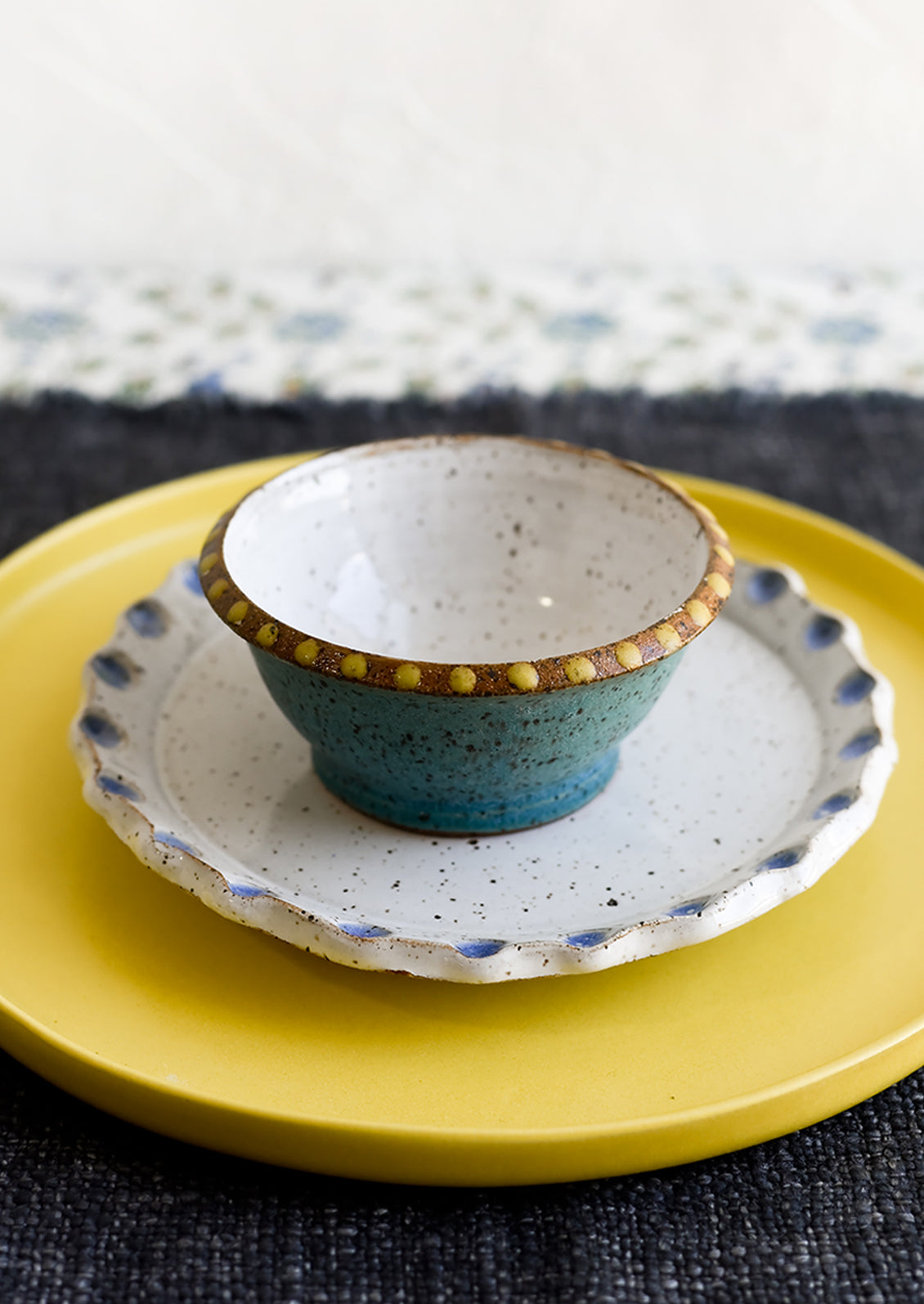A small turquoise ceramic bowl with yellow dot painted detailing.