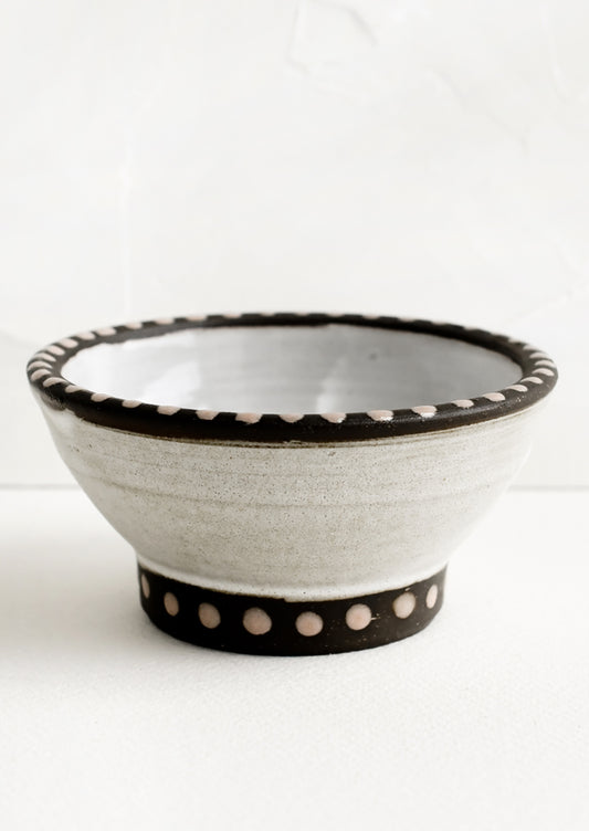 A small ceramic bowl with pink dot painted detailing.