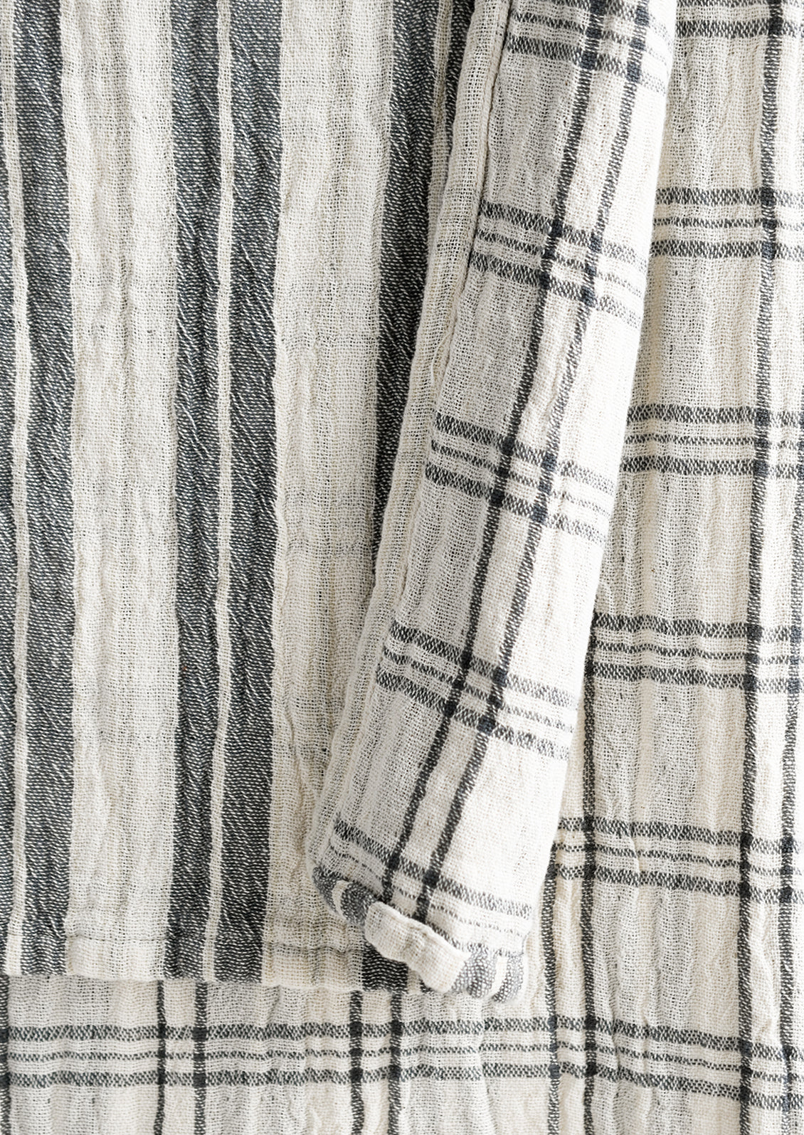 A gauzy table runner with stripes on front and check on back.