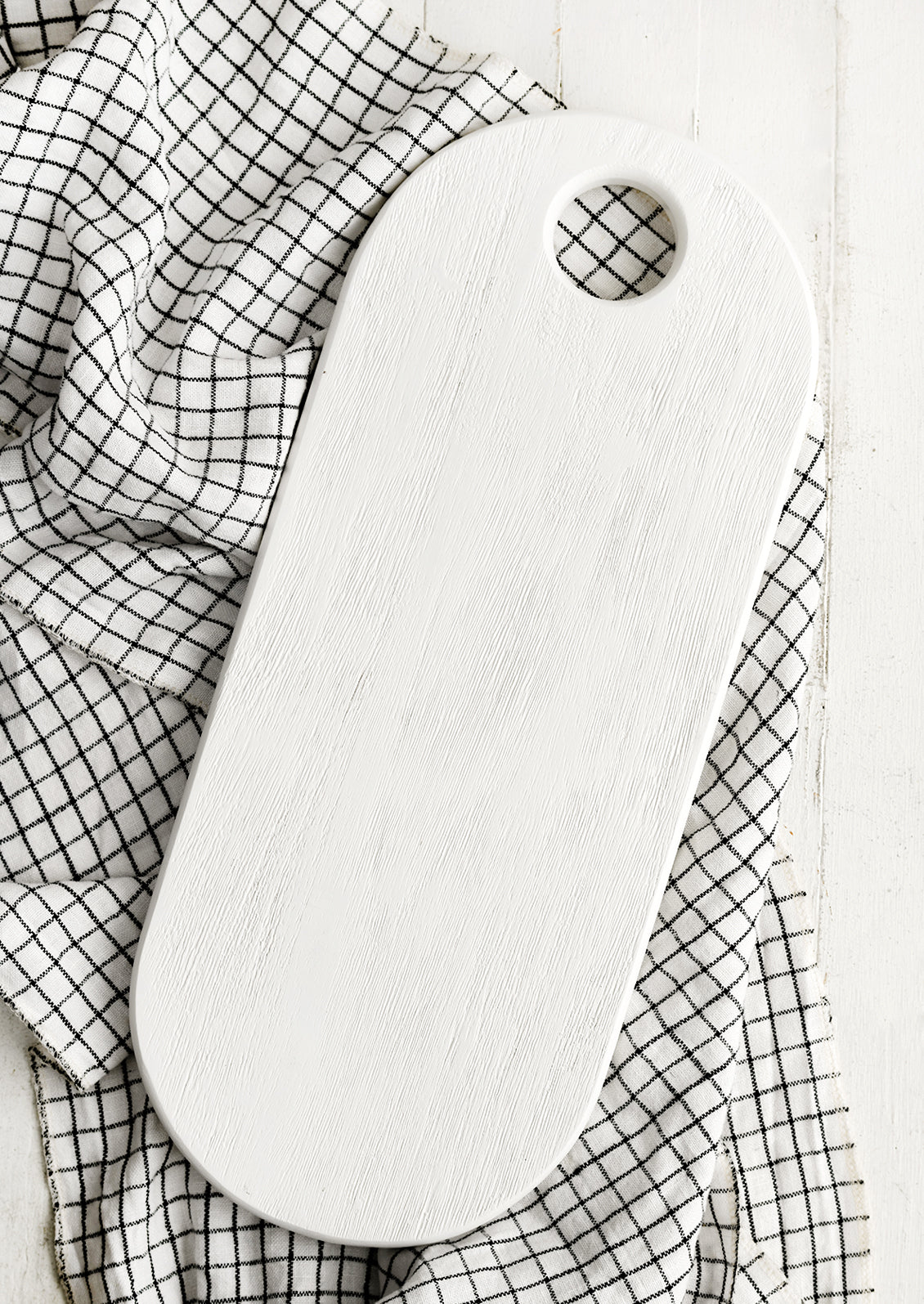 A long oval shaped wooden board with white wood finish.