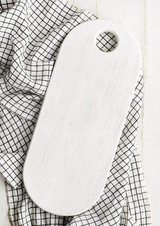 A long oval shaped wooden board with white wood finish.