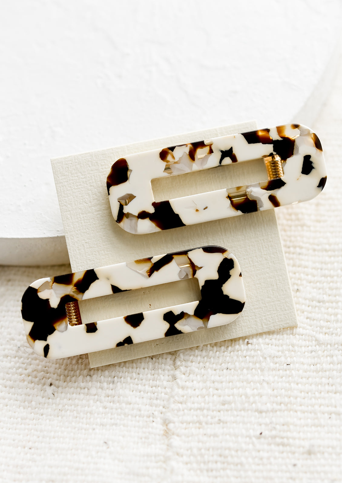 A pair of open rectangle shaped acetate hair clips in coco cream tortoiseshell print.