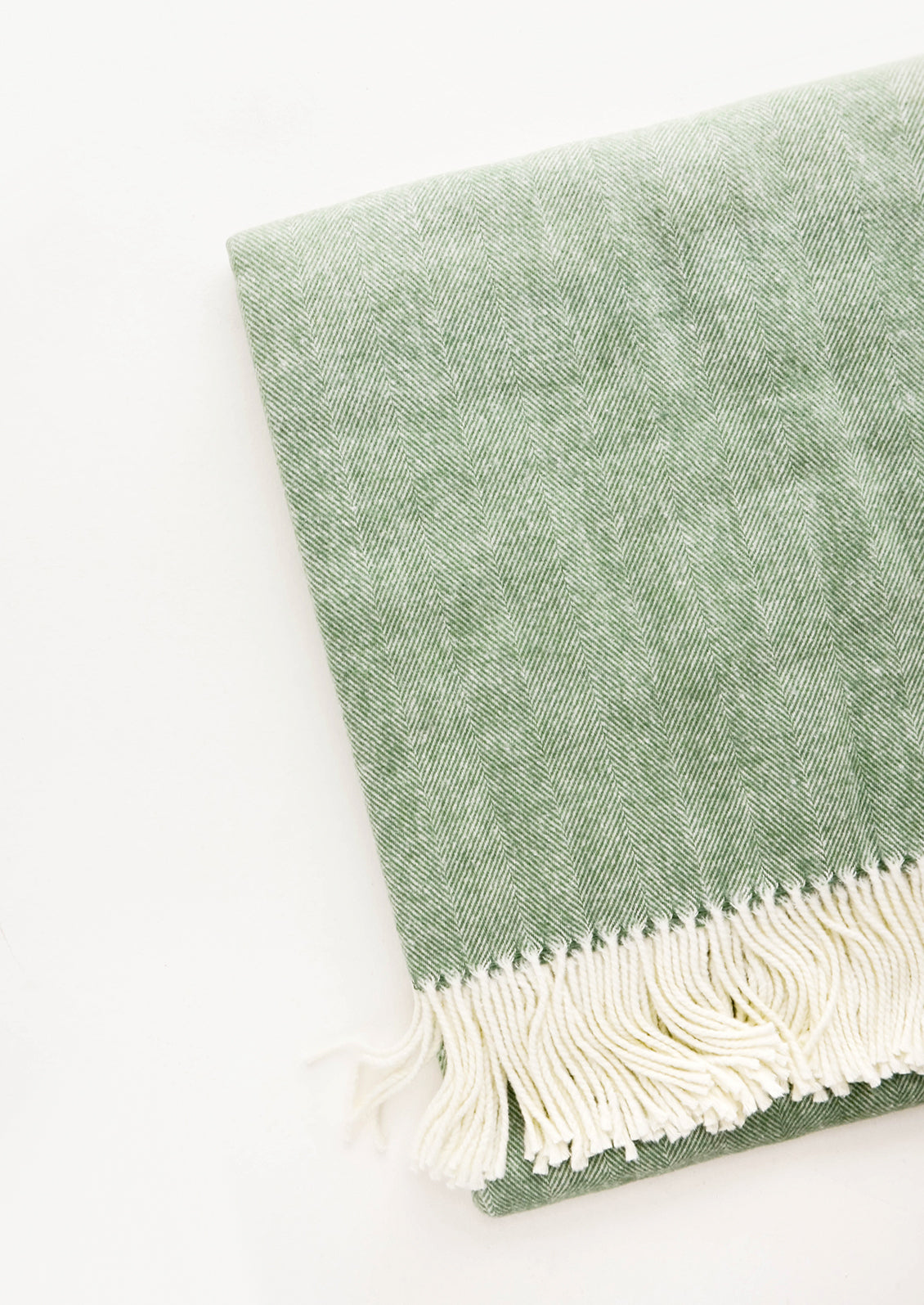 Green throw blanket in fine herringbone weave and ivory tassel trim