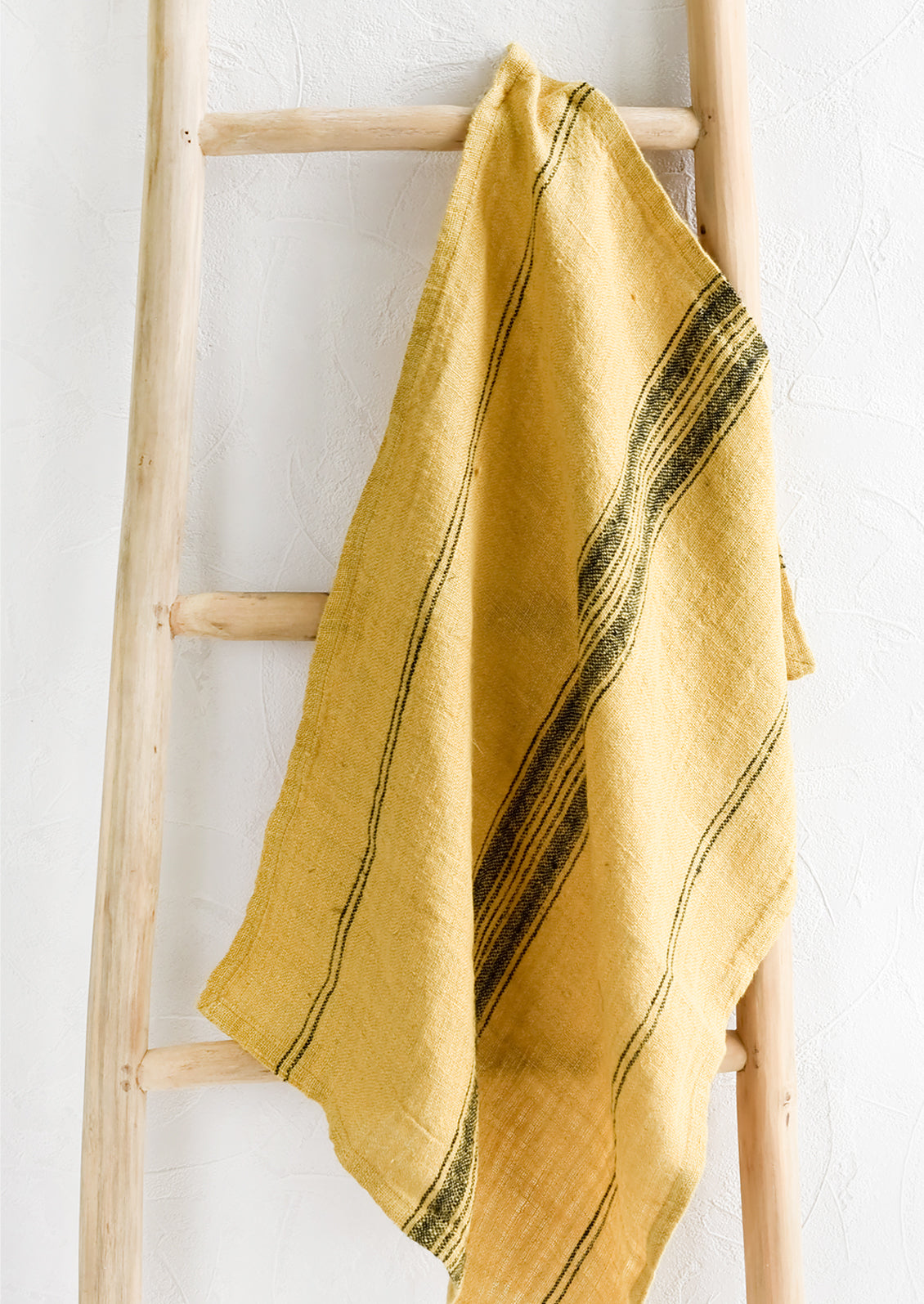 A woven tea towel in yellow with black stripe.