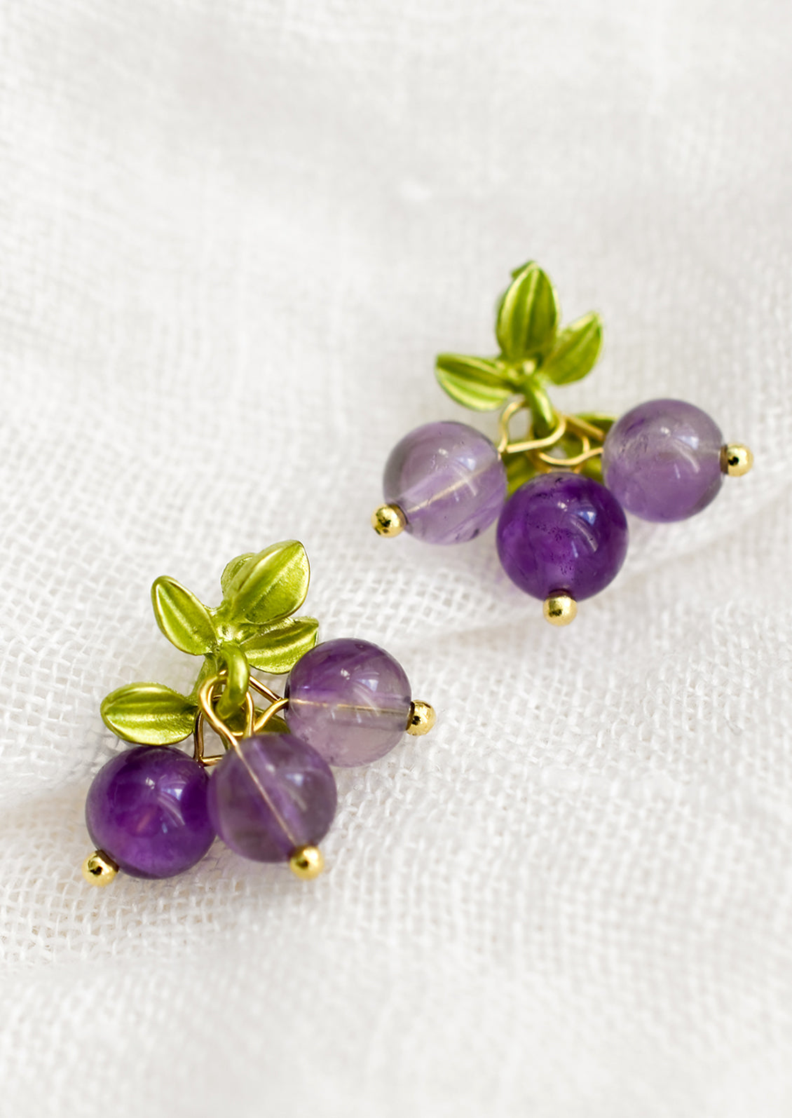 A pair of earrings made to resemble grapes, made with round amethyst beads.
