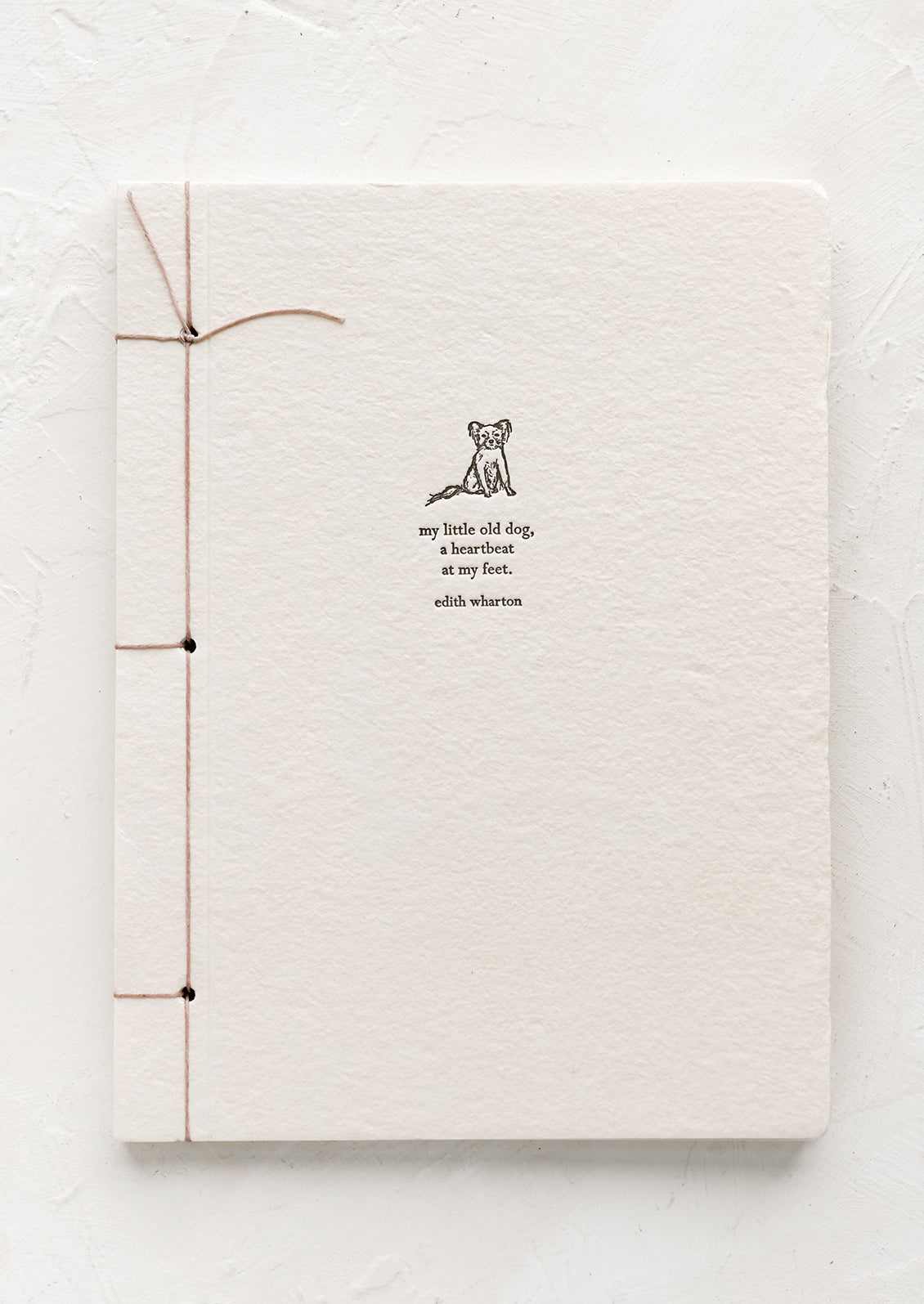 A journal with pale pink cover with Edith Wharton quote.