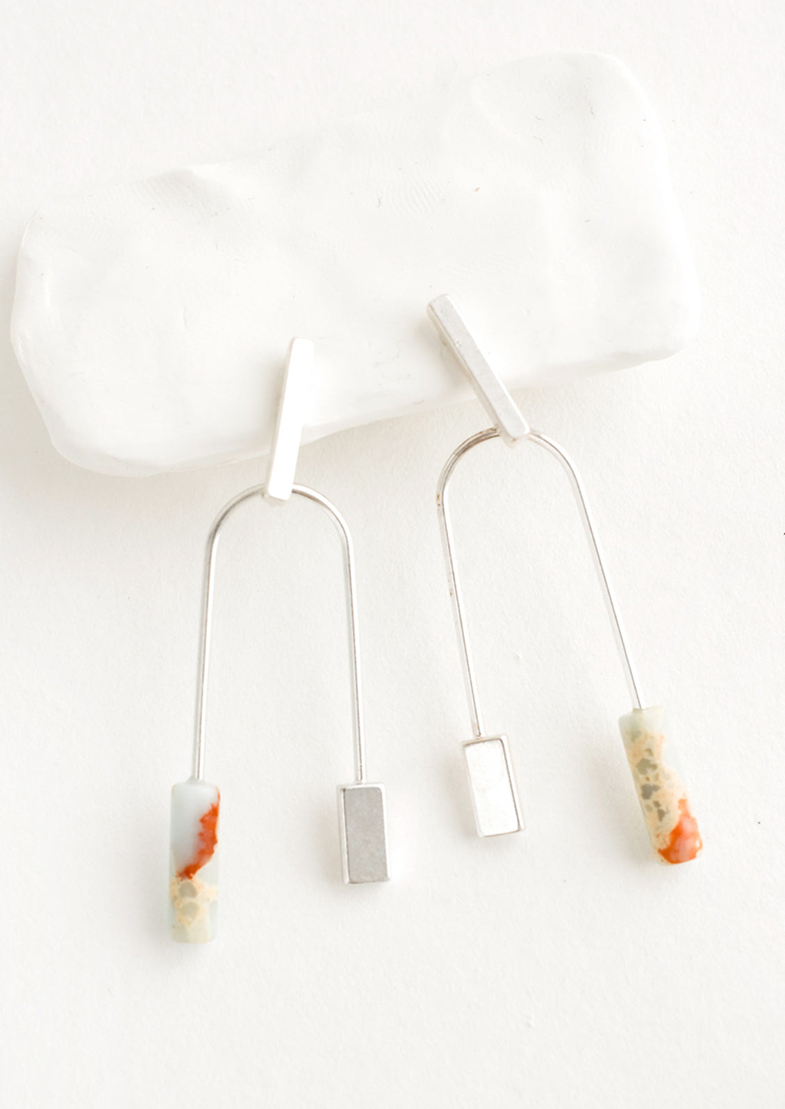 A pair of silver earrings with bar shaped top and arched bottom with mint gemstone on one side.