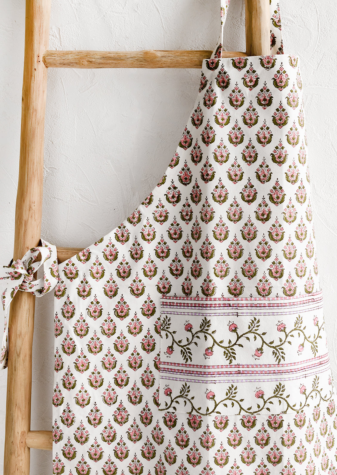 A printed apron in pink, green and lavender floral block print.