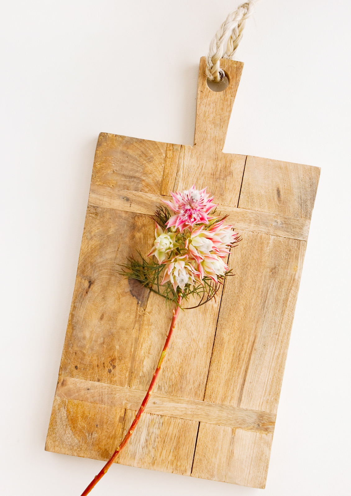 Rectangular wooden cutting board with rustic look, displayed with flowers.
