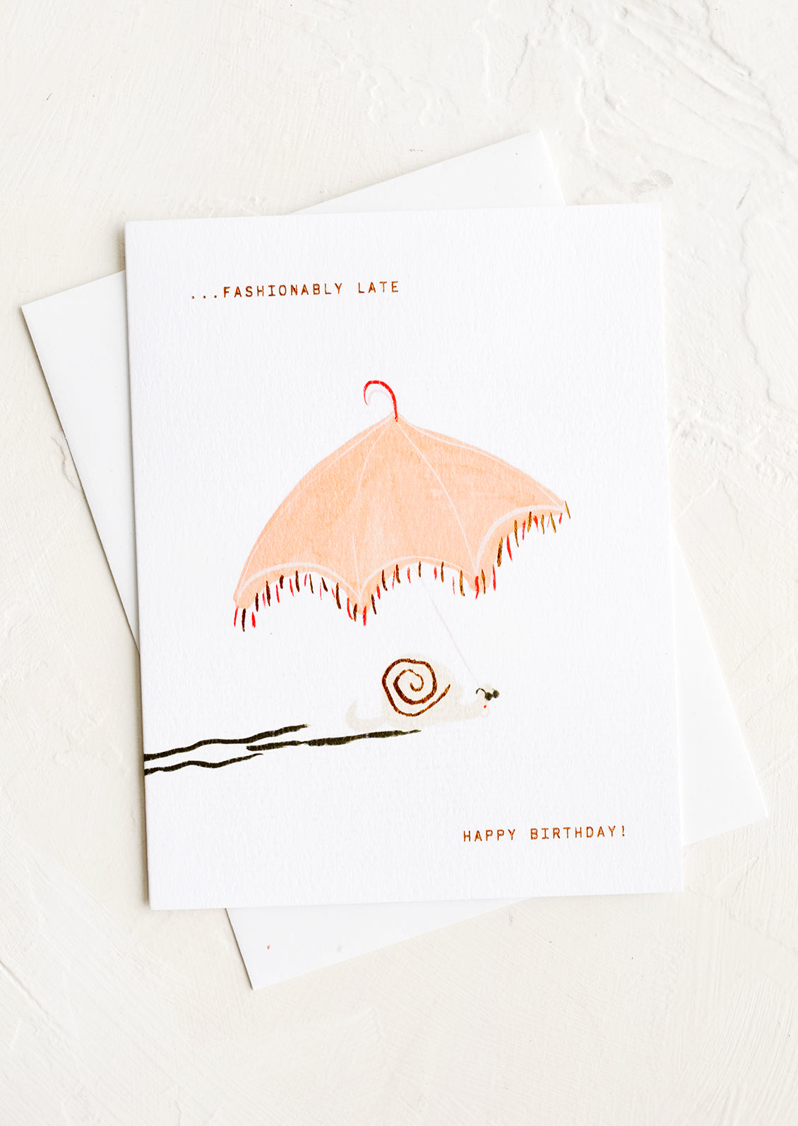 A greeting card with image of snail and parasol, text reading "Fashionably late, happy birthday!"