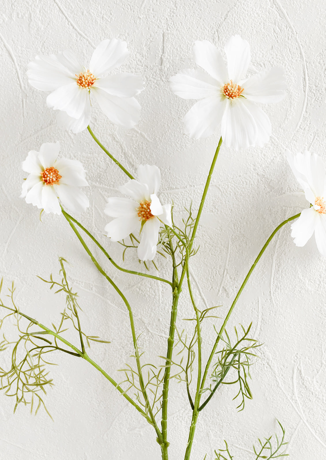 An artificial floral spray of white cosmos flowers.