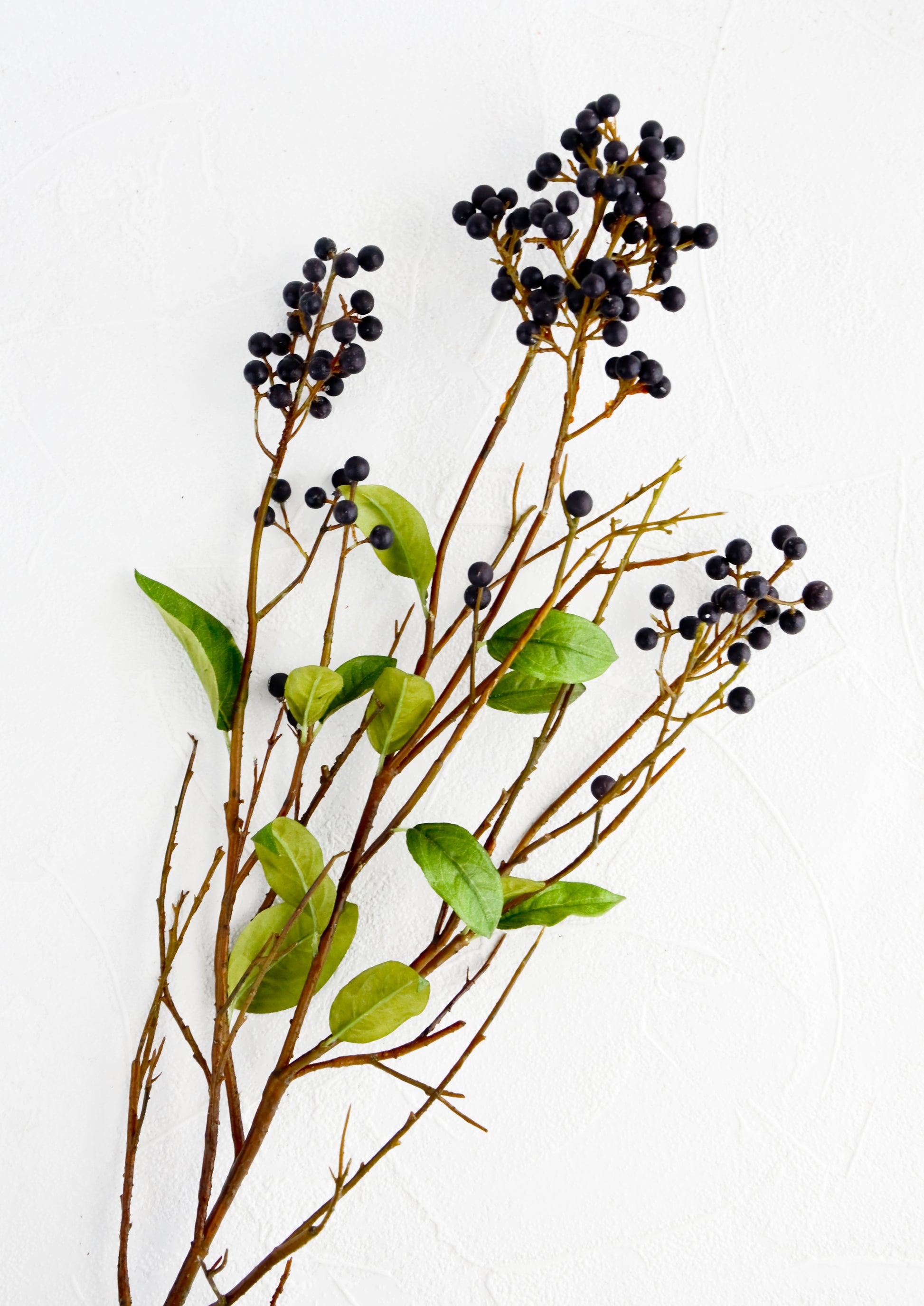 Faux branches with green leaves and dark blue privet berries.