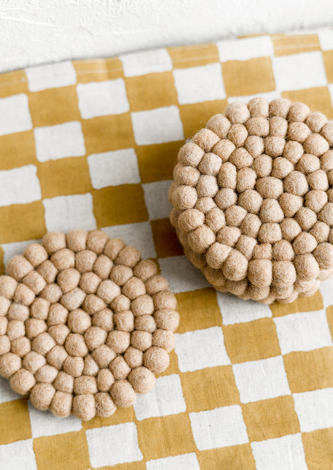 A set of round felted wool coasters in coffee.