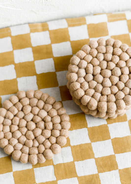 A set of round felted wool coasters in coffee.